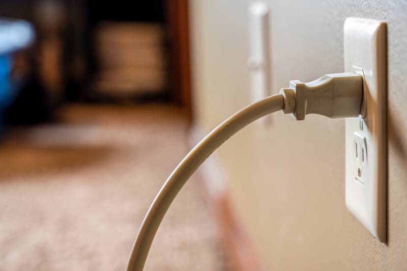 Plugged electrical outlet on beige wall.