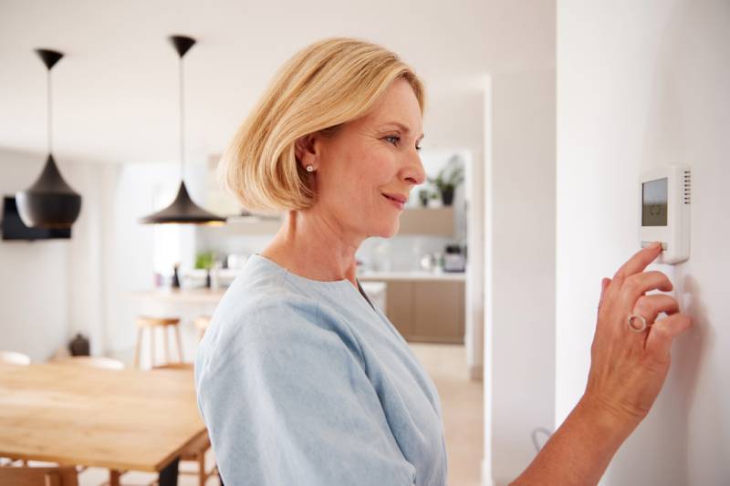 Woman adjusting home thermostat