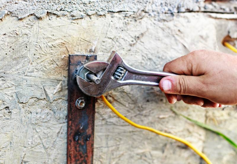 Hand tightening bolt with wrench on grounding wire.