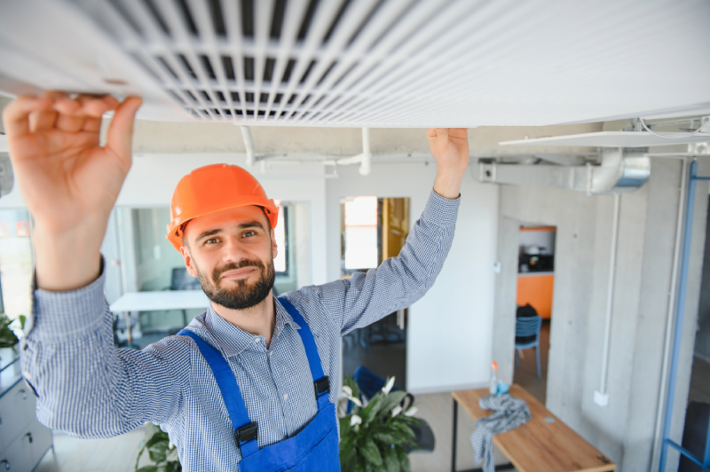 Technician fixing ceiling AC unit.