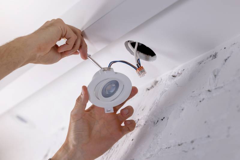 Person installing an LED light fixture in a ceiling.