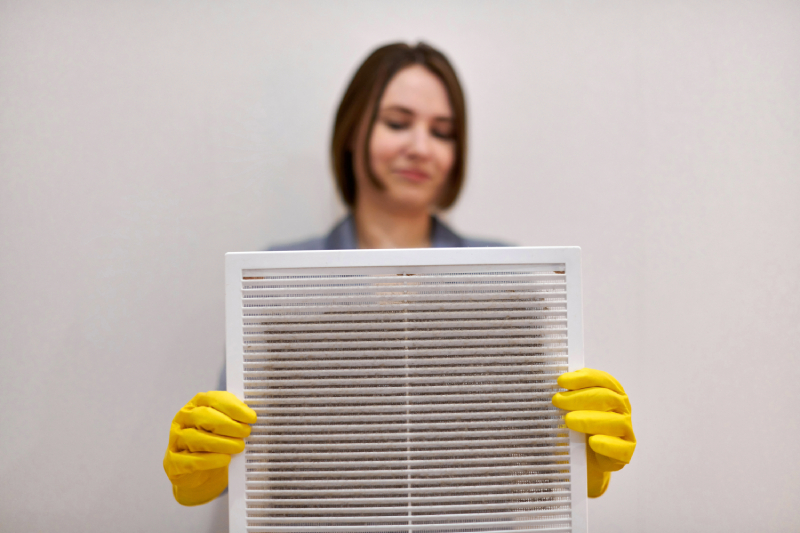 Woman holding dirty air filter, smiling.