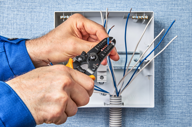 Person using wire stripper on electrical box wiring