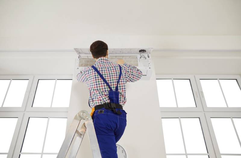 Technician servicing wall-mounted AC unit.
