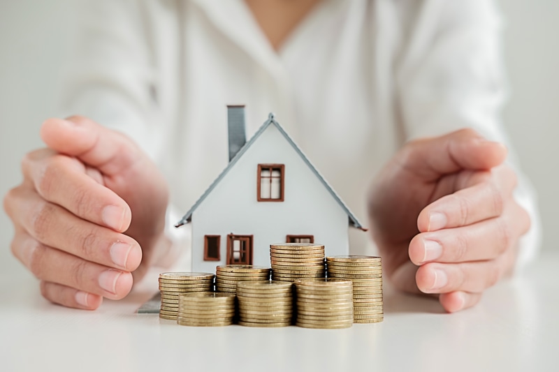 Miniature house, stacked coins, hands护
