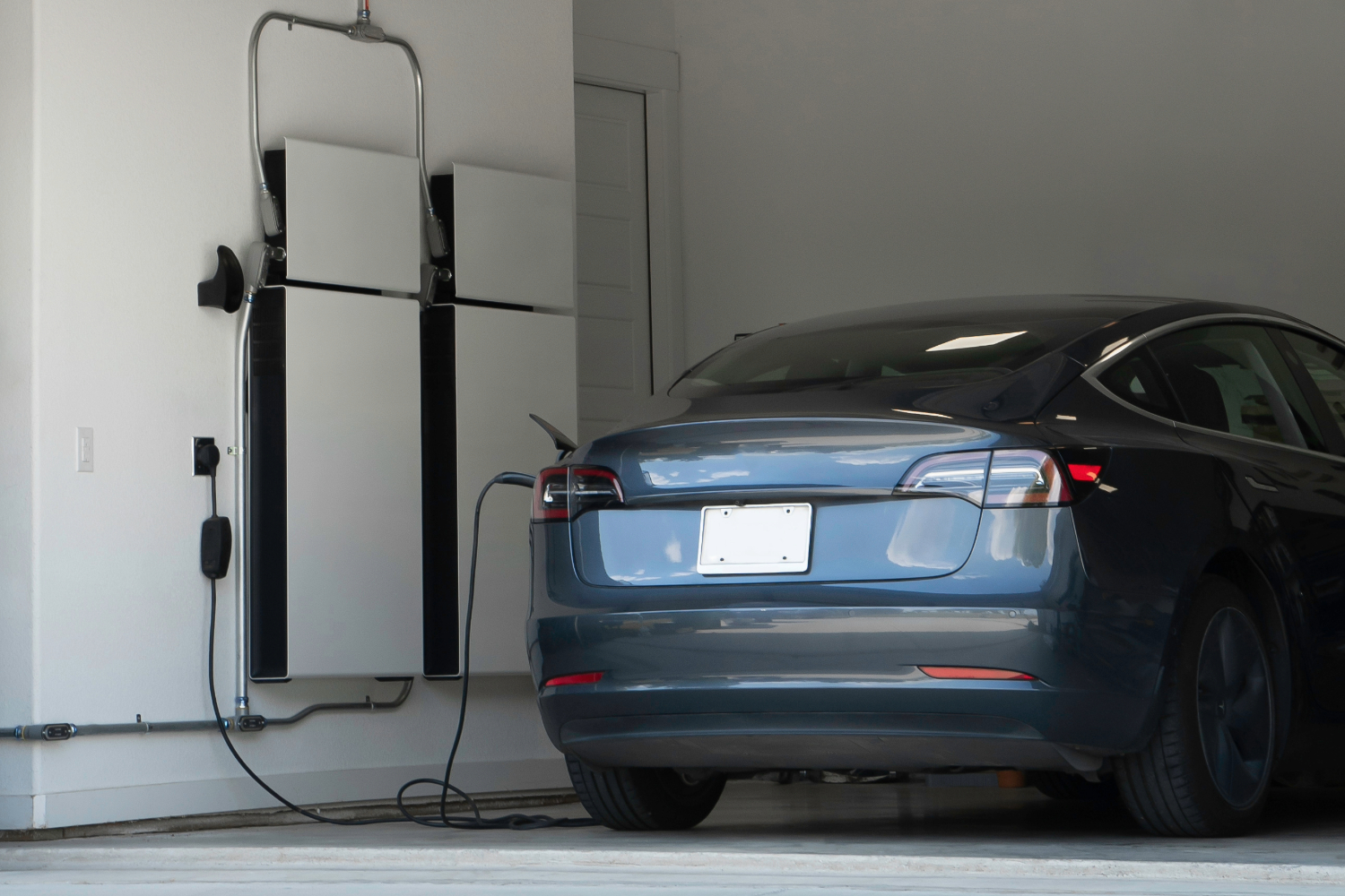 Tesla car charging in garage with mounted EV charger