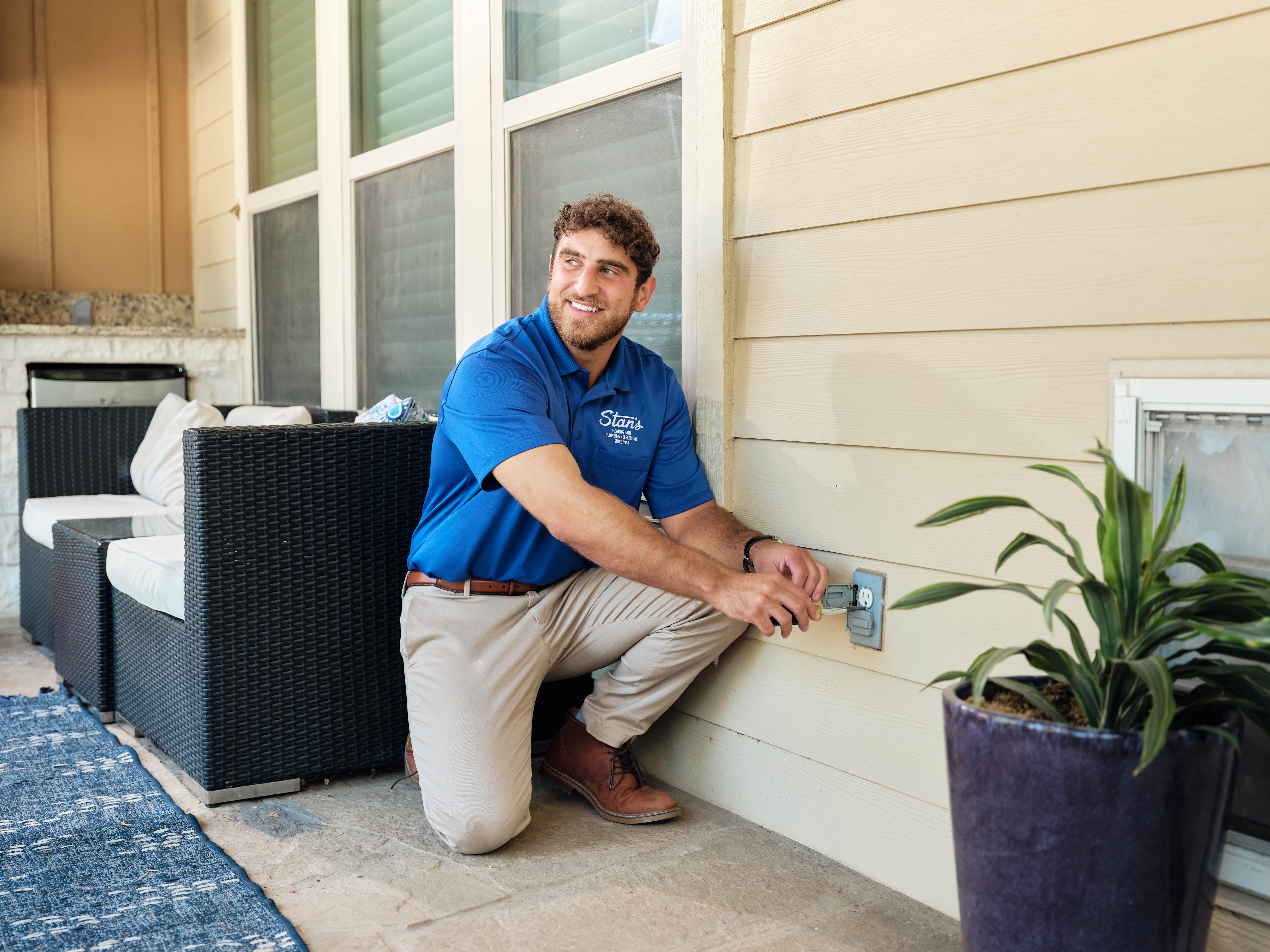 Technician in blue shirt fixing outdoor electrical outlet.