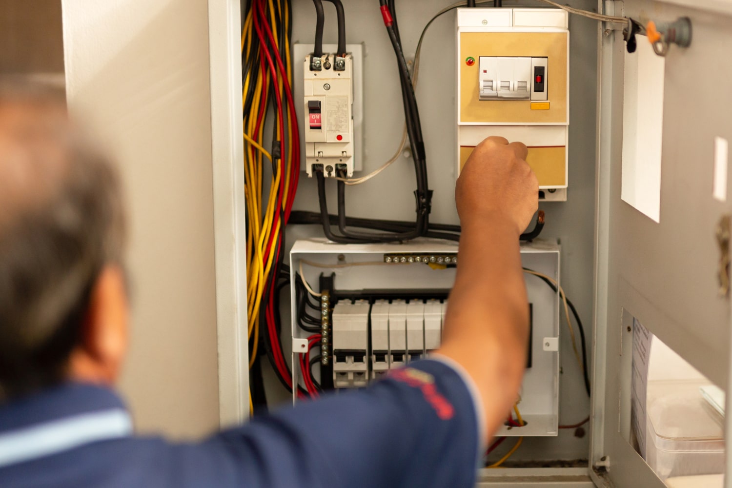 Technician adjusts electrical panel wiring.
