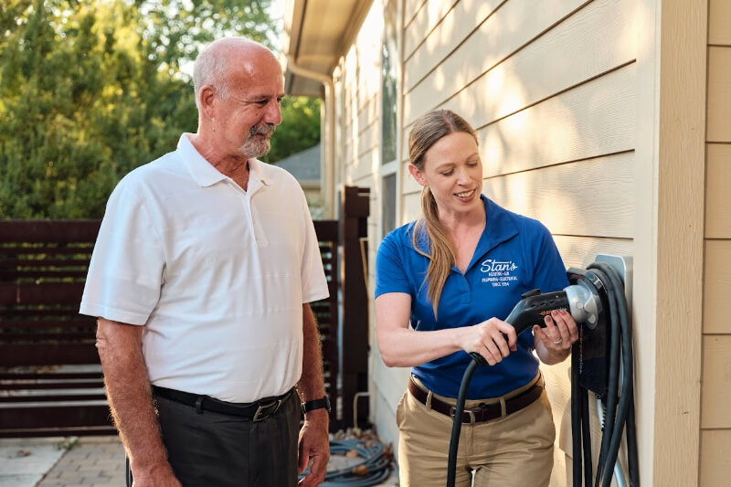 Woman demonstrating EV charger to man outside house