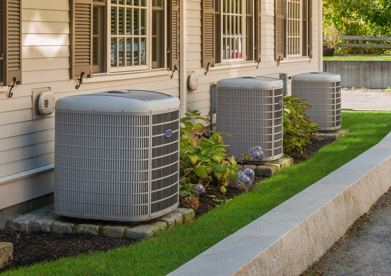 Three outdoor AC units by a house.