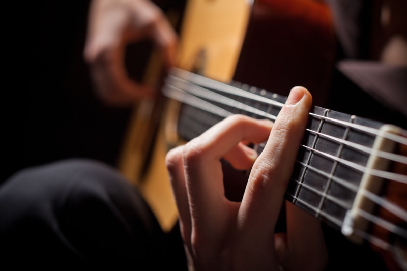 Close-up of fingers playing guitar strings.