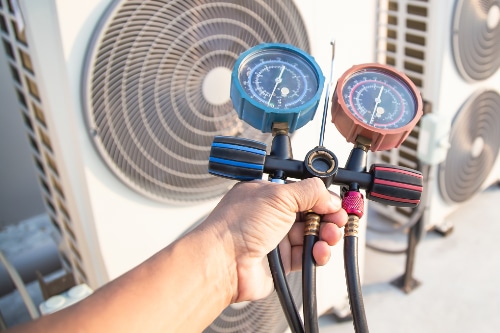 Hand holding AC pressure gauges near units