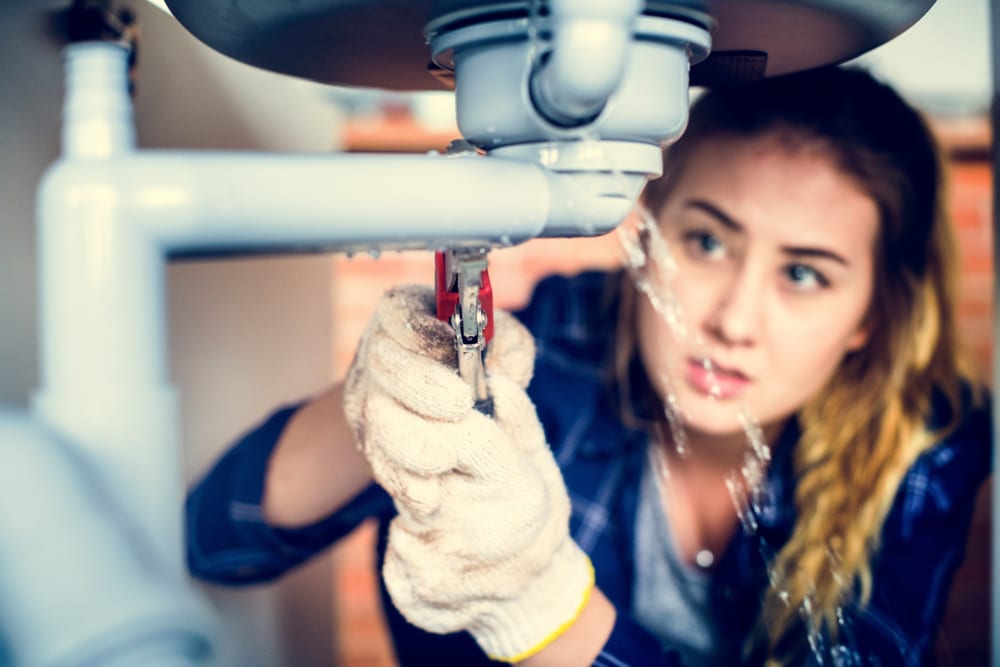 Woman repairing leaking pipe