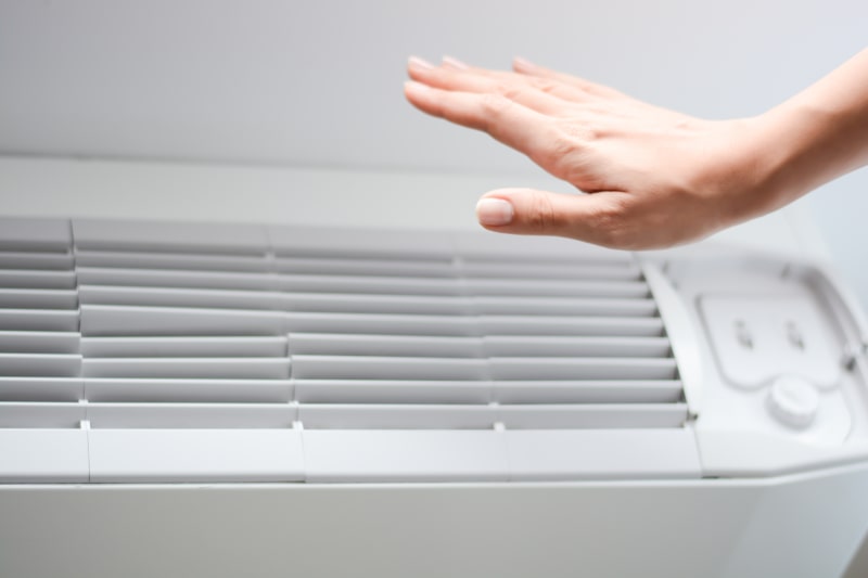 Hand above air conditioner vent.