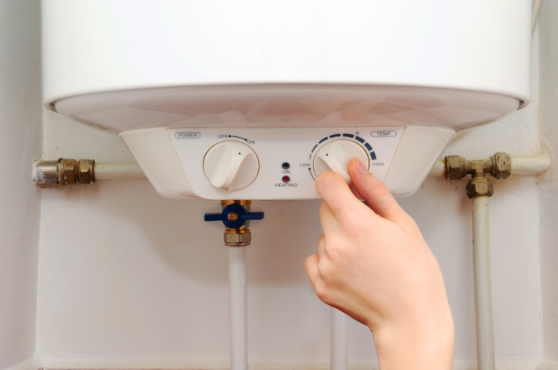Hand adjusting water heater temperature dial