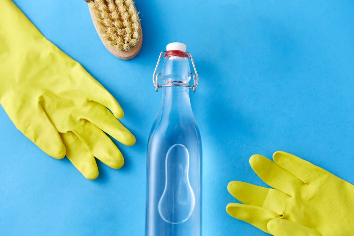 Clear bottle, yellow gloves, scrub brush on blue.
