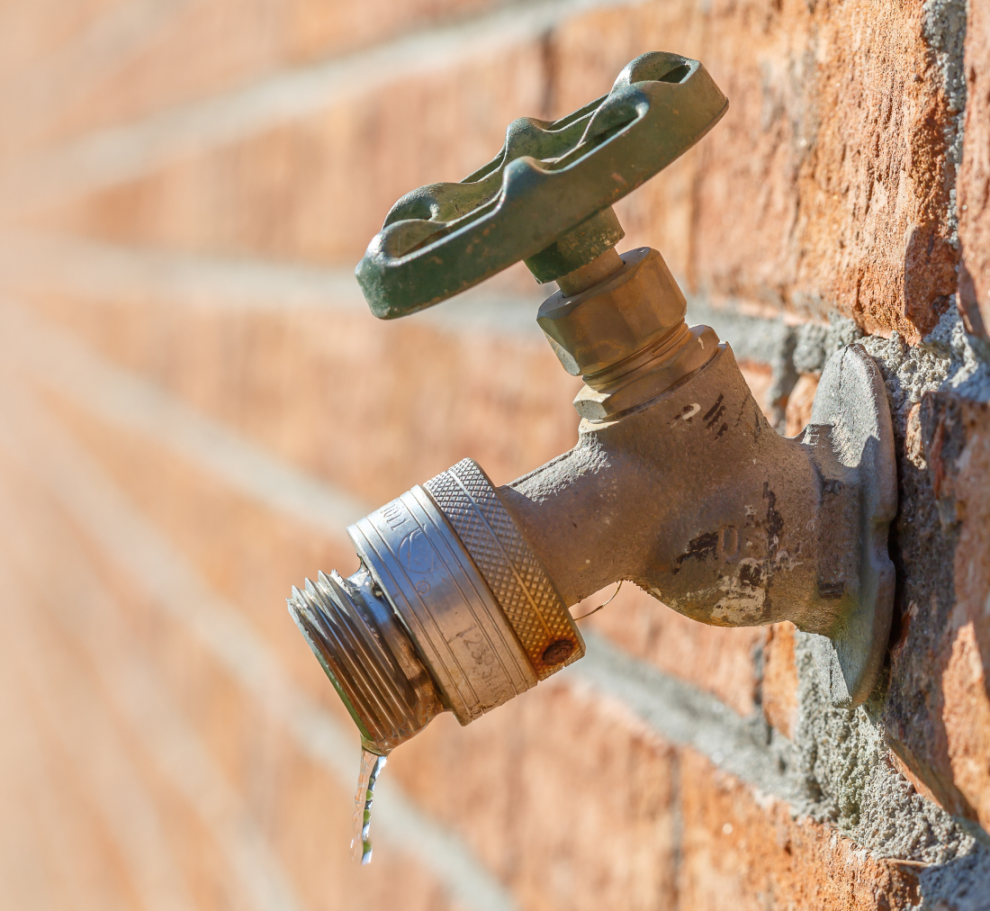 Dripping hose bib on brick wall