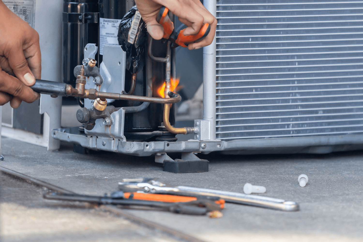 Person attempting DIY AC repair with tools and flame.