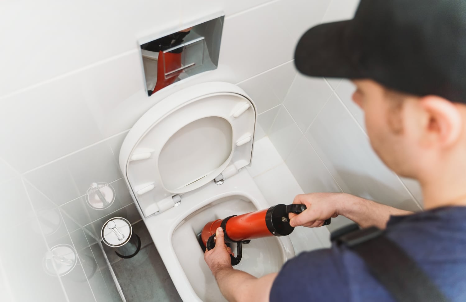 Plumber using force pump to unclog toilet.