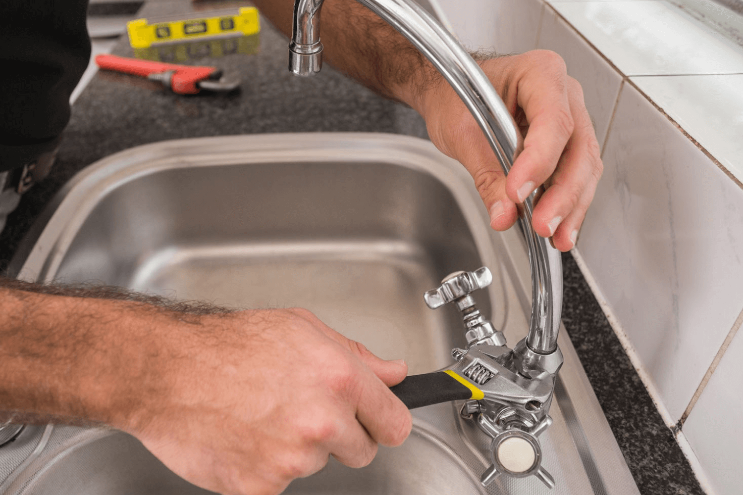 Plumber tightening kitchen faucet.