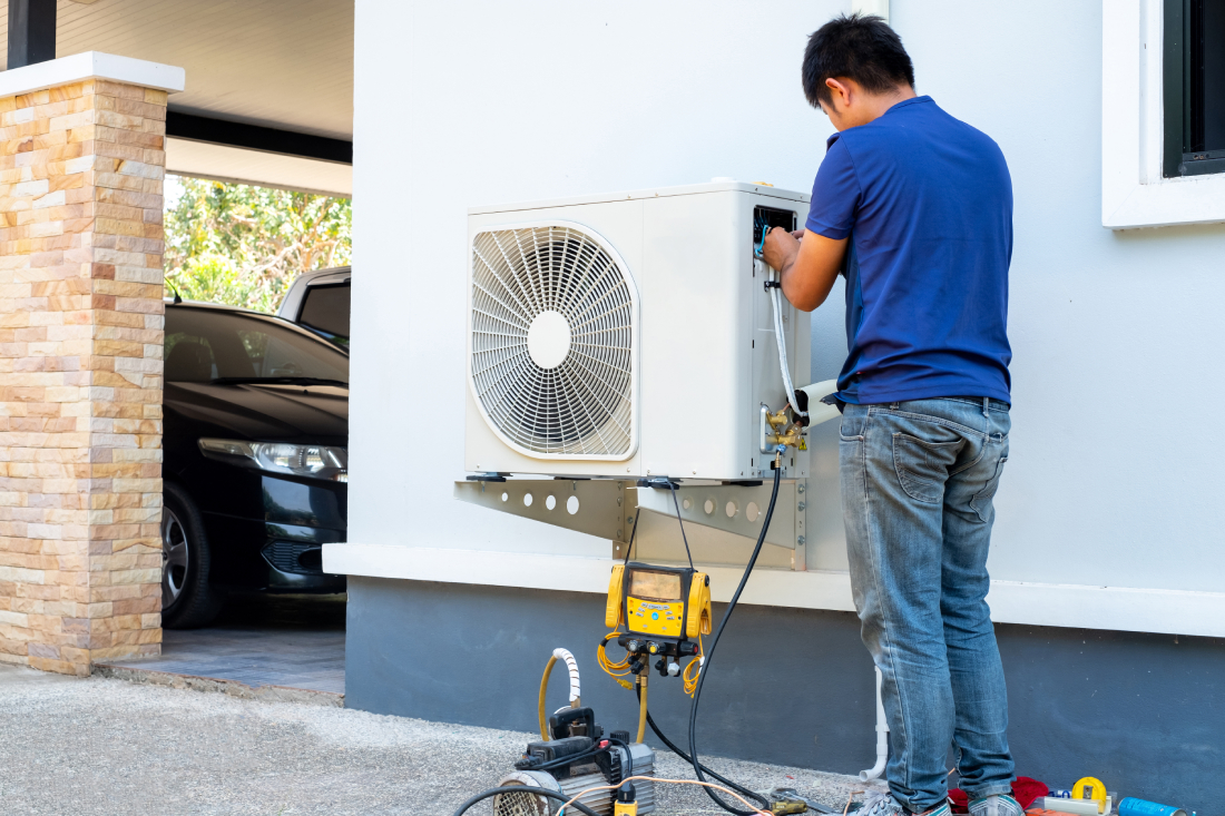 Technician repairing outdoor AC unit.