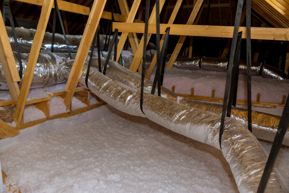 Attic insulation with flexible AC ducts, wooden trusses.
