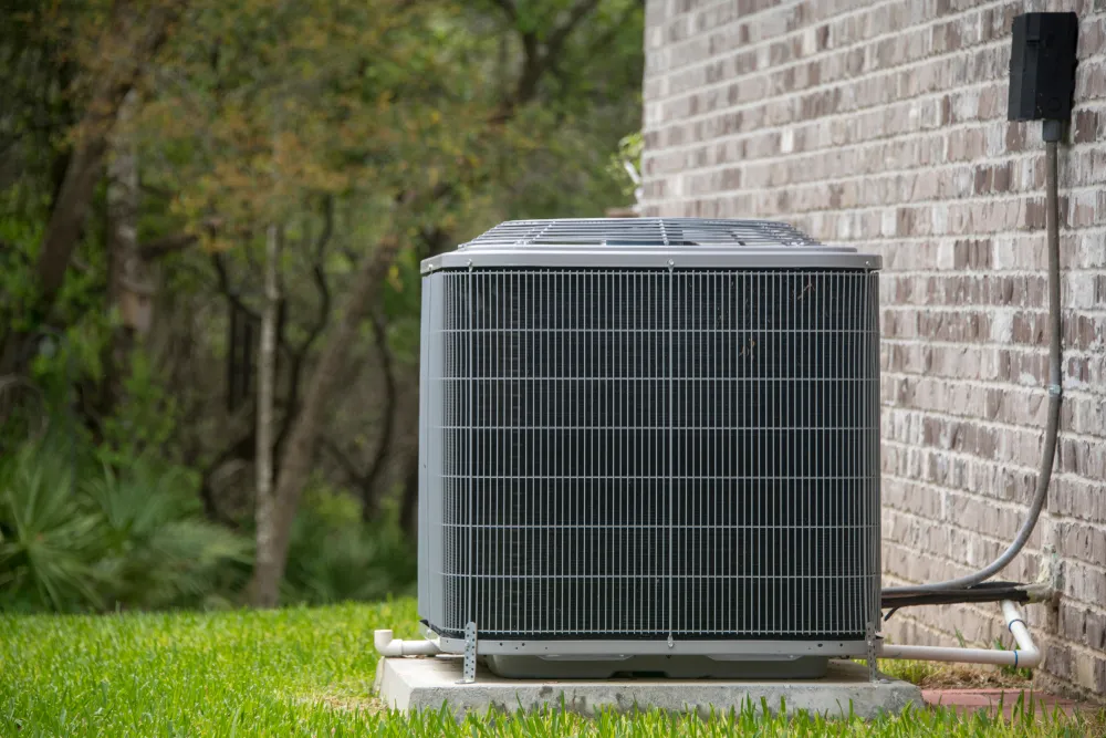 Outdoor AC unit next to brick wall.