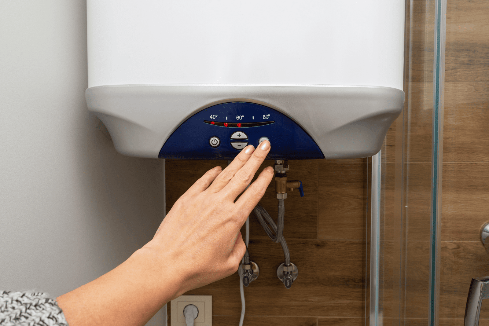 Person adjusting the temperature settings on a wall-mounted water heater.