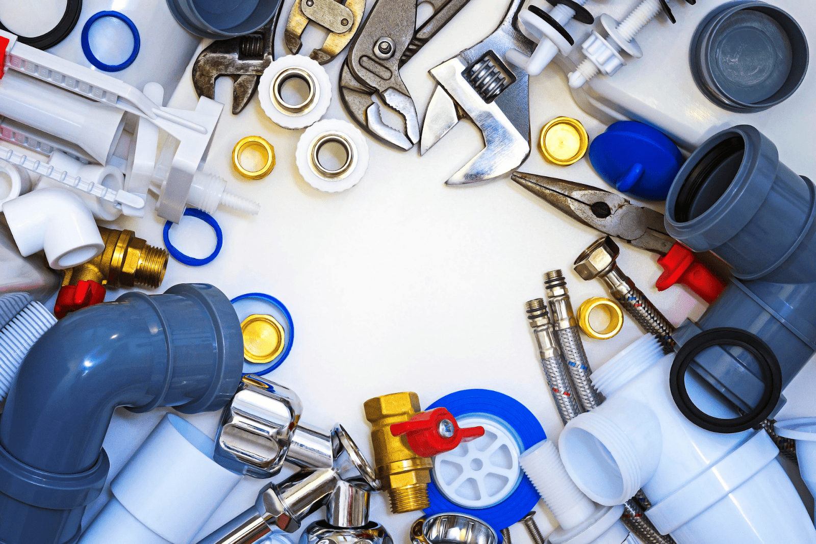 Assorted plumbing tools, pipes, and fittings arranged in a circular frame on a white background.