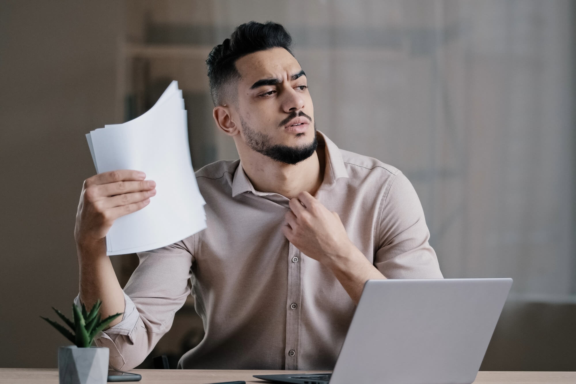 Man fanning himself with papers indoors