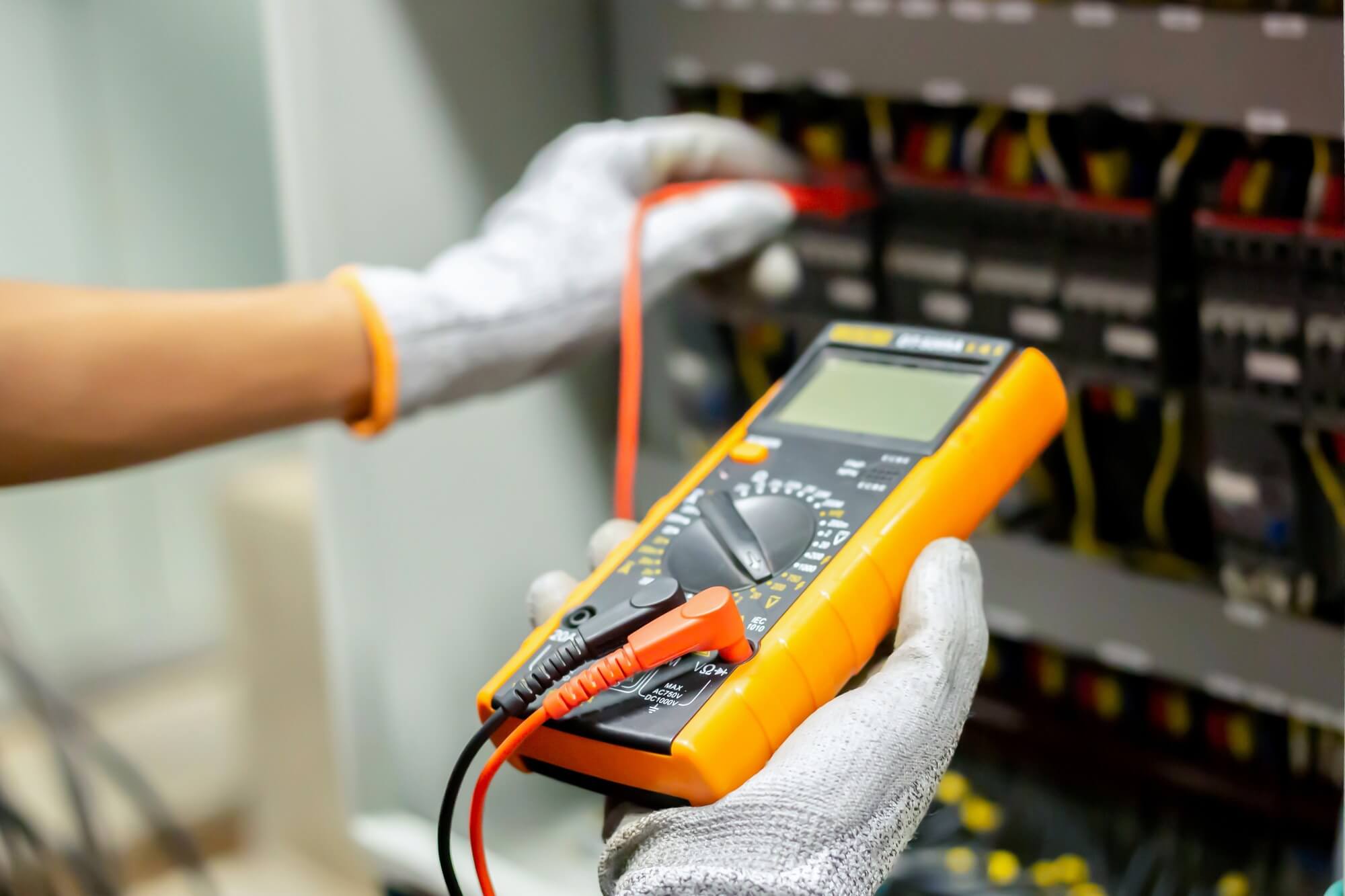 Electrician testing breakers with a handheld voltage meter.