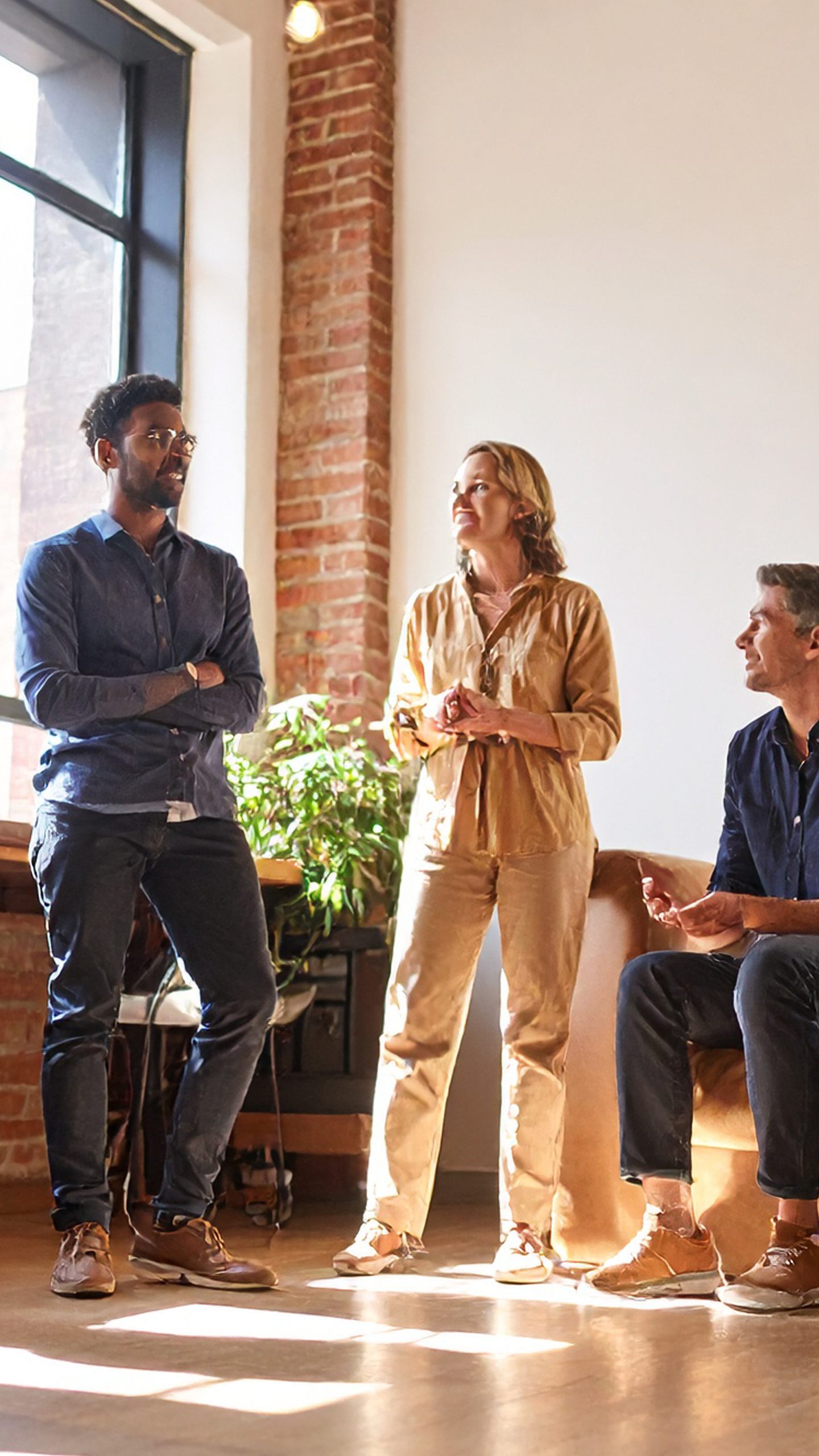 Colleagues talking together in a sunlit office with brick walls