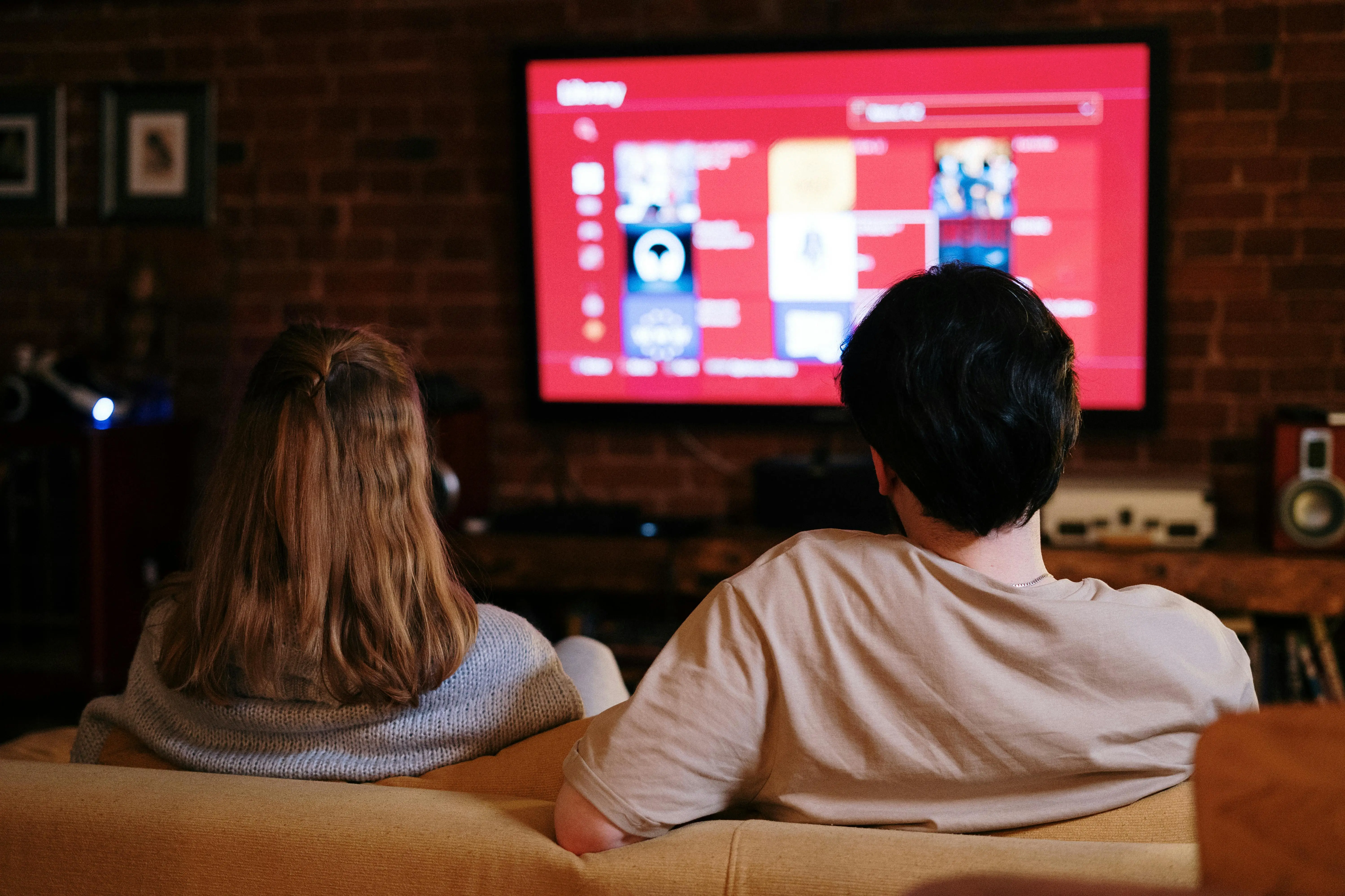 Couple sitting on a couch watching TV together, symbolizing the comfort and relaxation possible when recurring cleaning services keep the home consistently tidy.