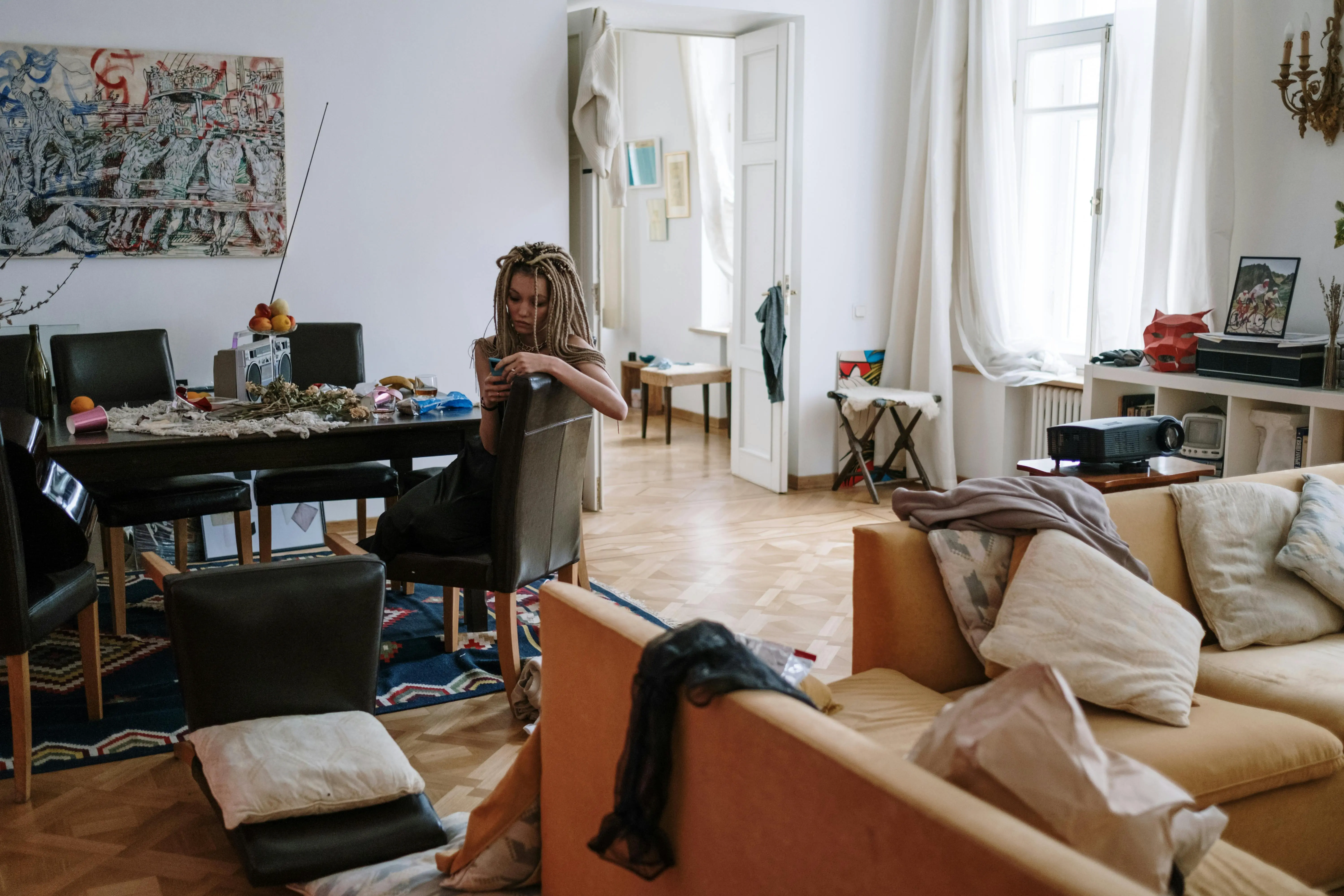 Woman sitting in a cluttered living room highlighting how a messy home increases stress and affects mental health and sleep quality.