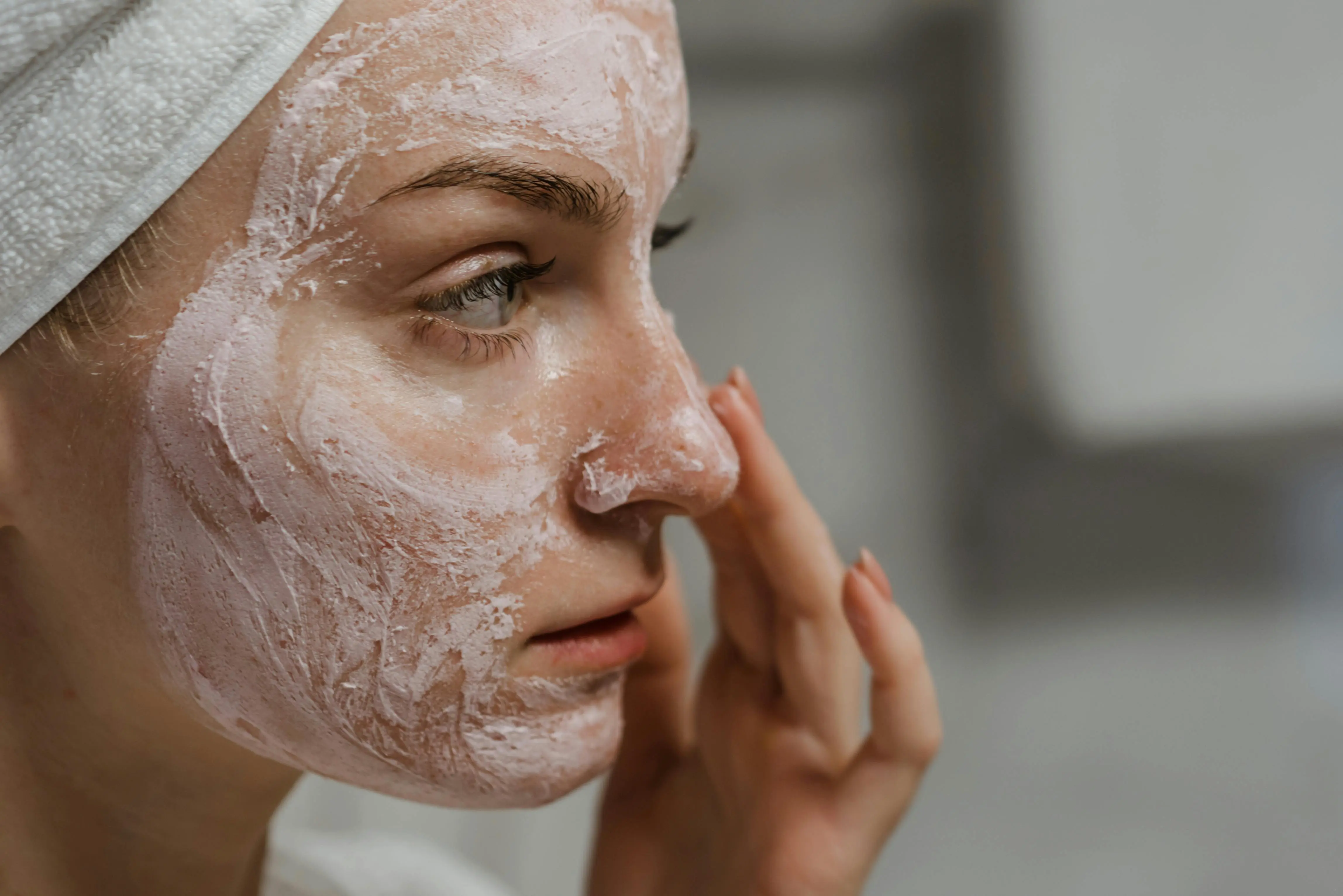  Woman practicing self-care with a face mask, connecting cleanliness, skincare, and mental well-being in a clean home.