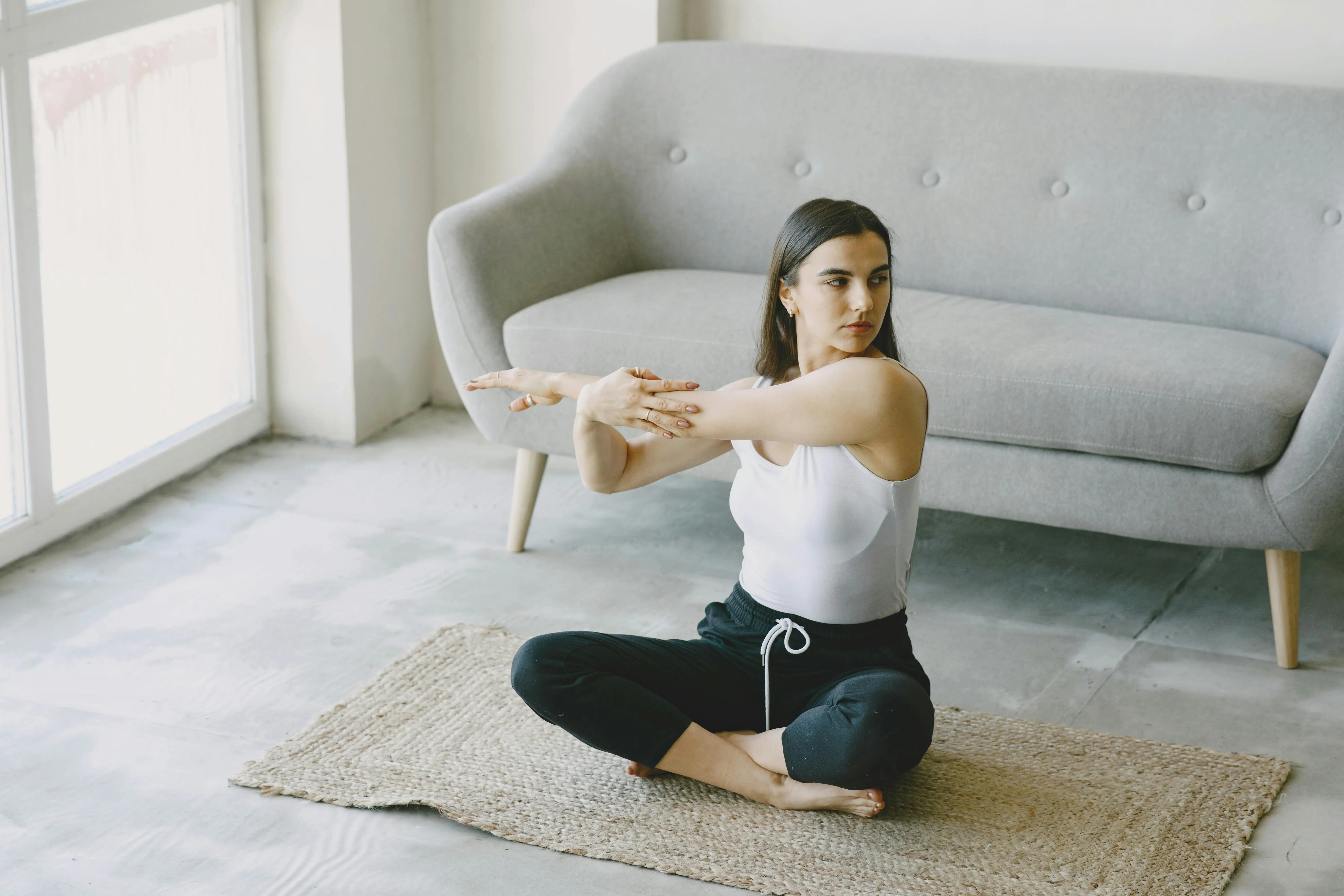 Woman doing yoga in a clean home environment, showing how a tidy space promotes relaxation, focus, and better sleep.