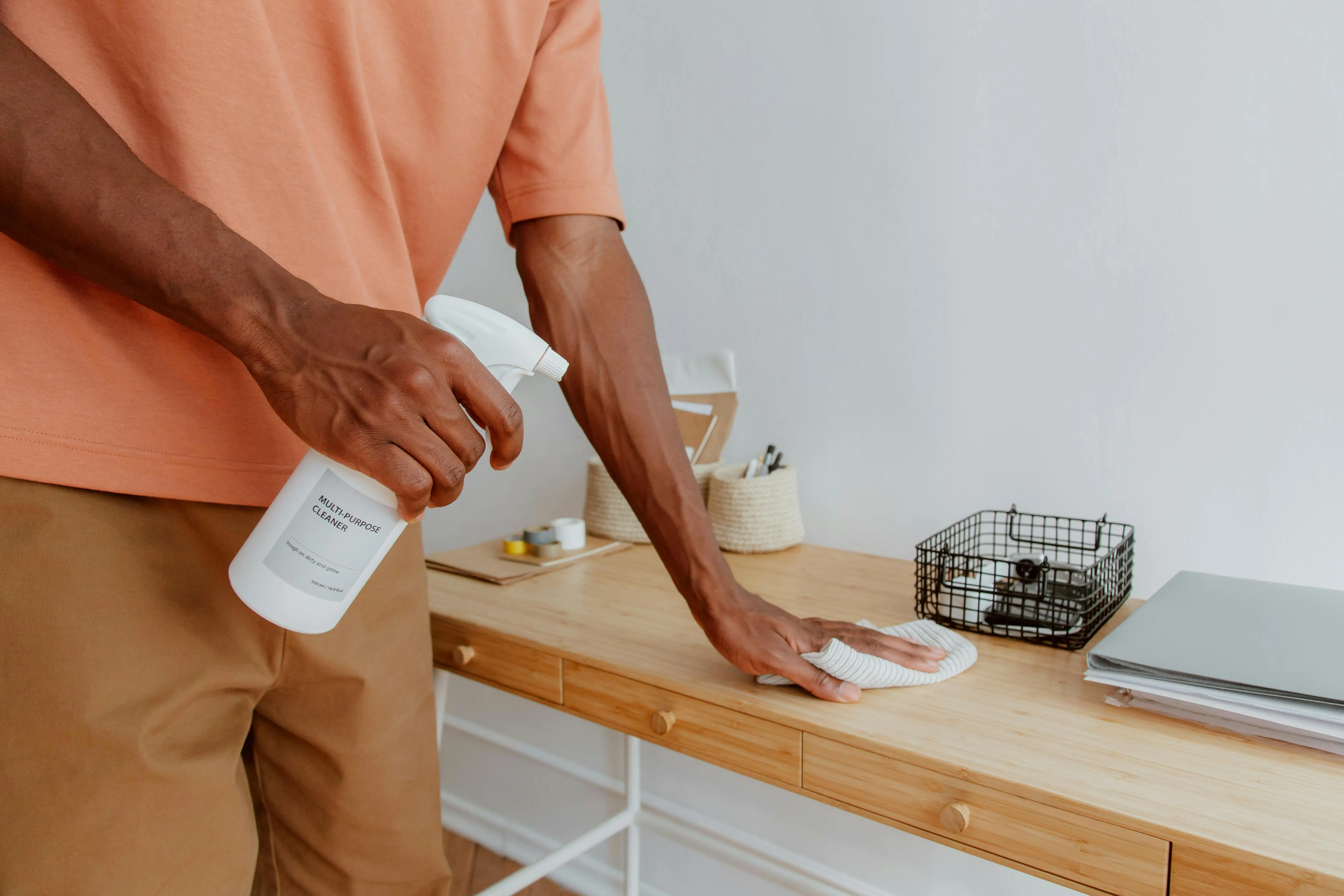 Man cleaning wooden counter with spray bottle — budget-friendly house cleaning tip for Toronto families using affordable DIY supplies.