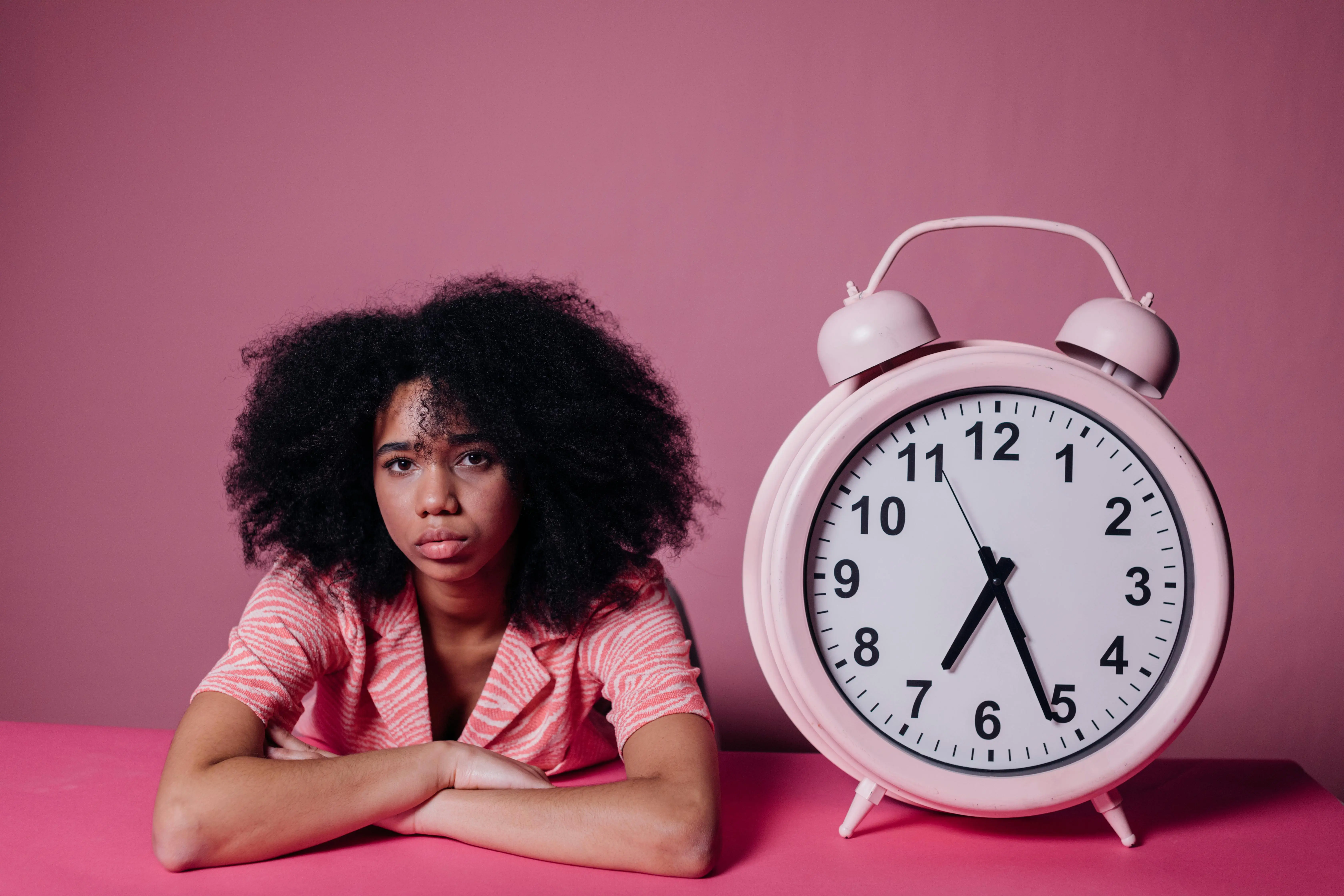  Stressed woman sitting beside a large clock, representing lack of time for DIY cleaning compared to hiring Etobicoke professional cleaning services.
