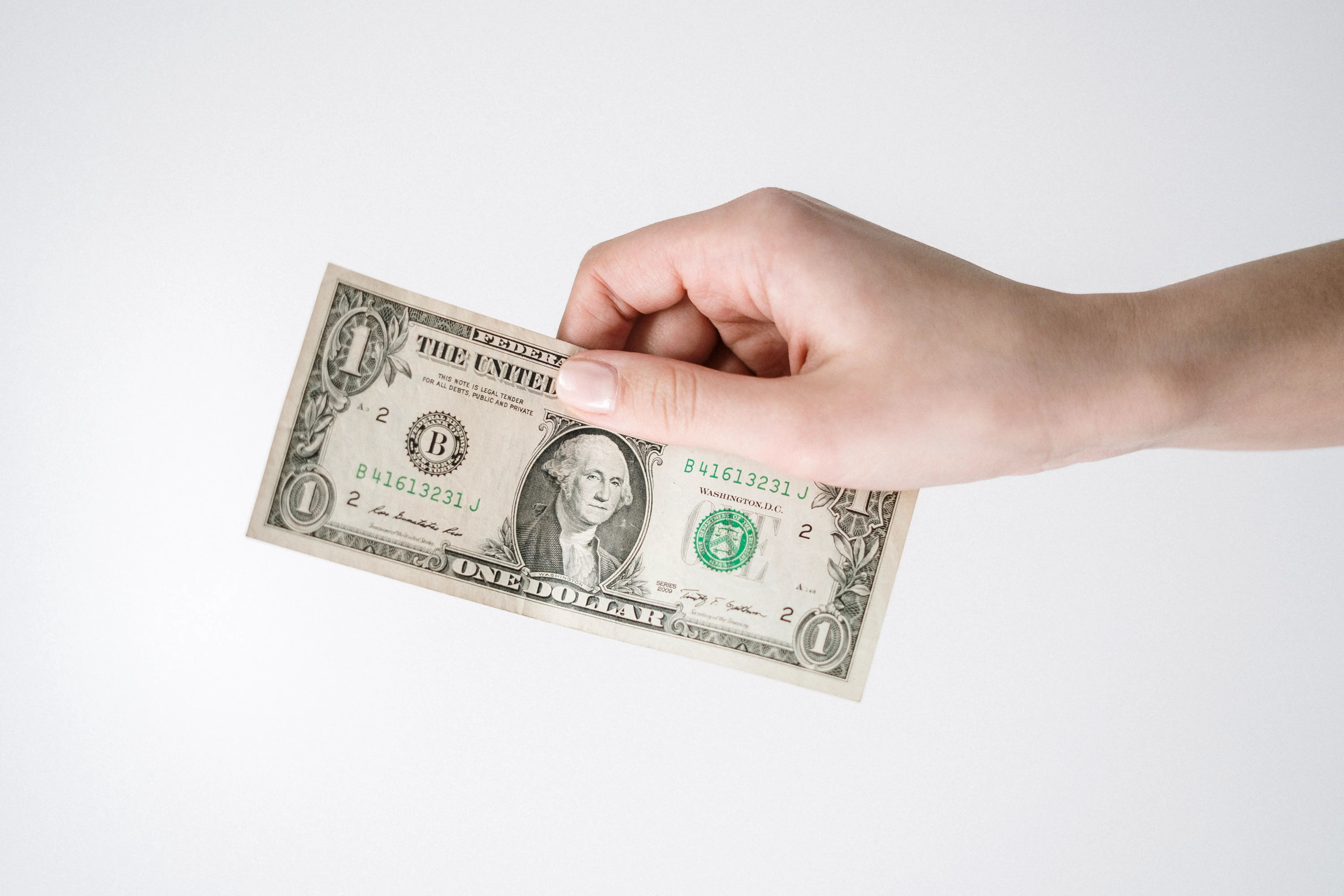 Hand holding cash, deciding whether to tip a house cleaner