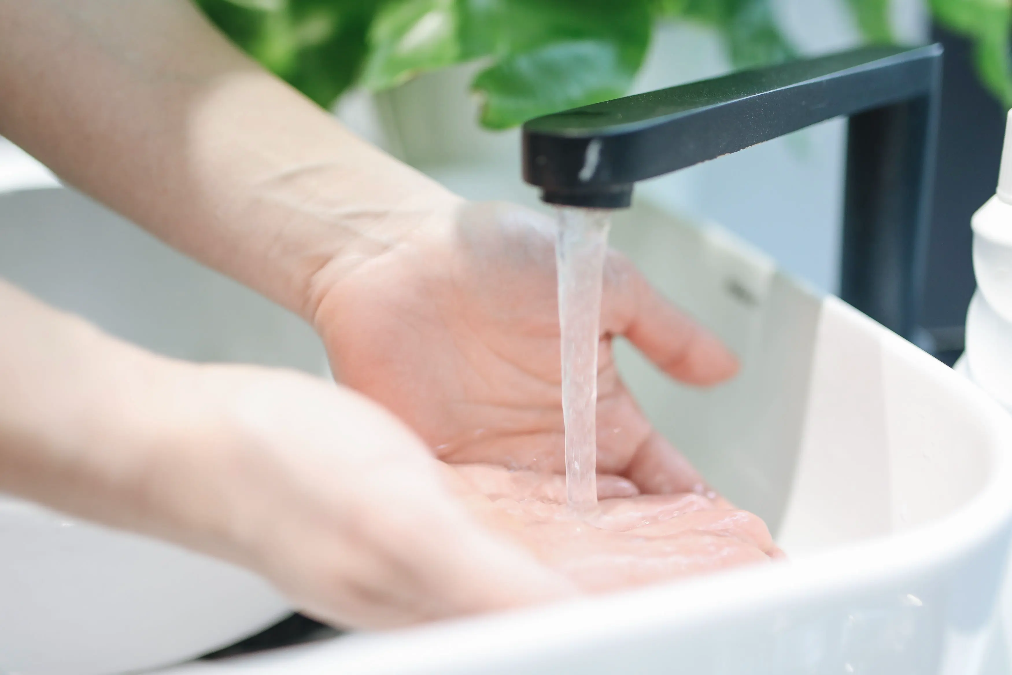 Tap water running over hands, showing Toronto's hard water from the faucet
