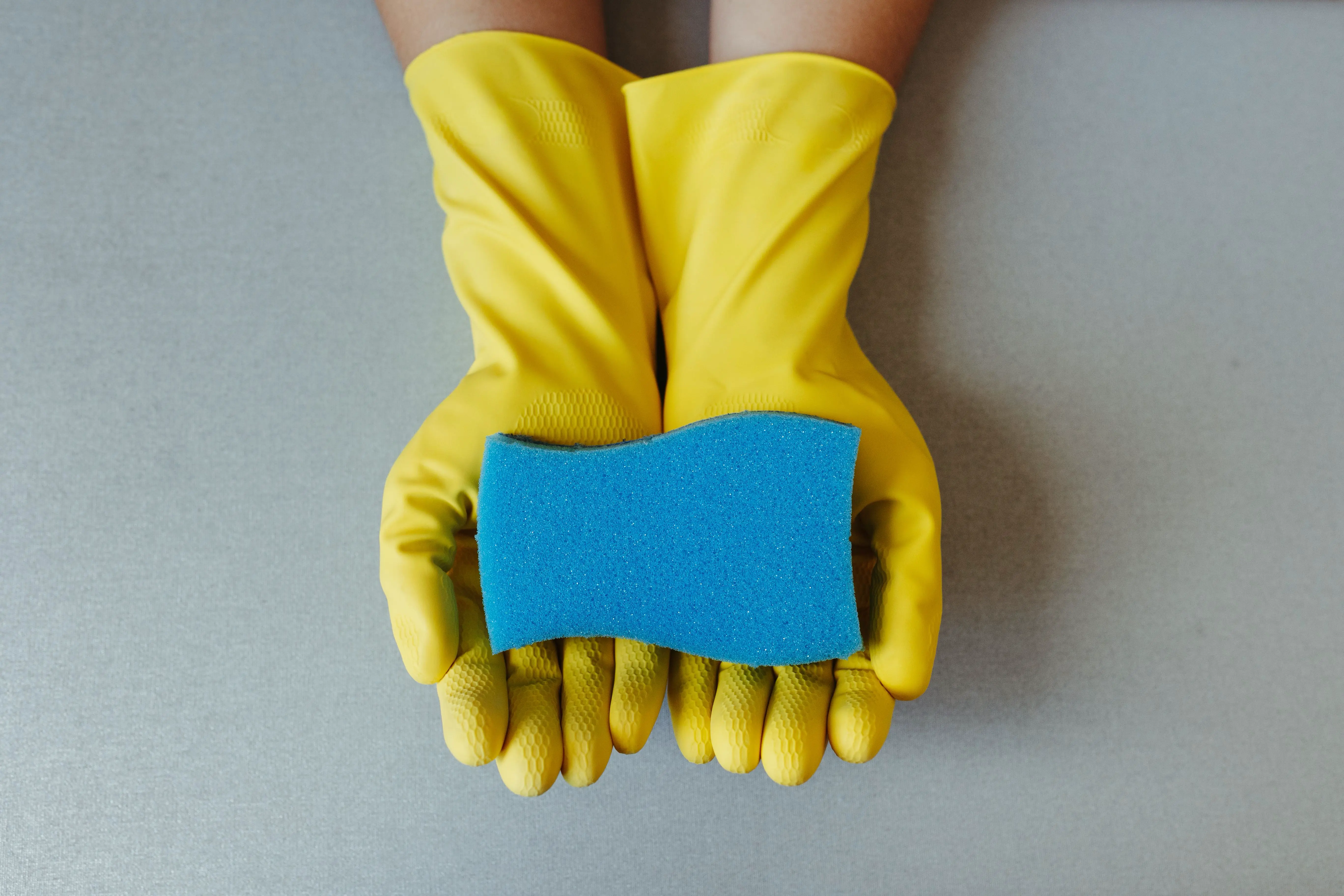 House cleaning in yellow gloves with a sponge, comparing standard and deep cleaning services