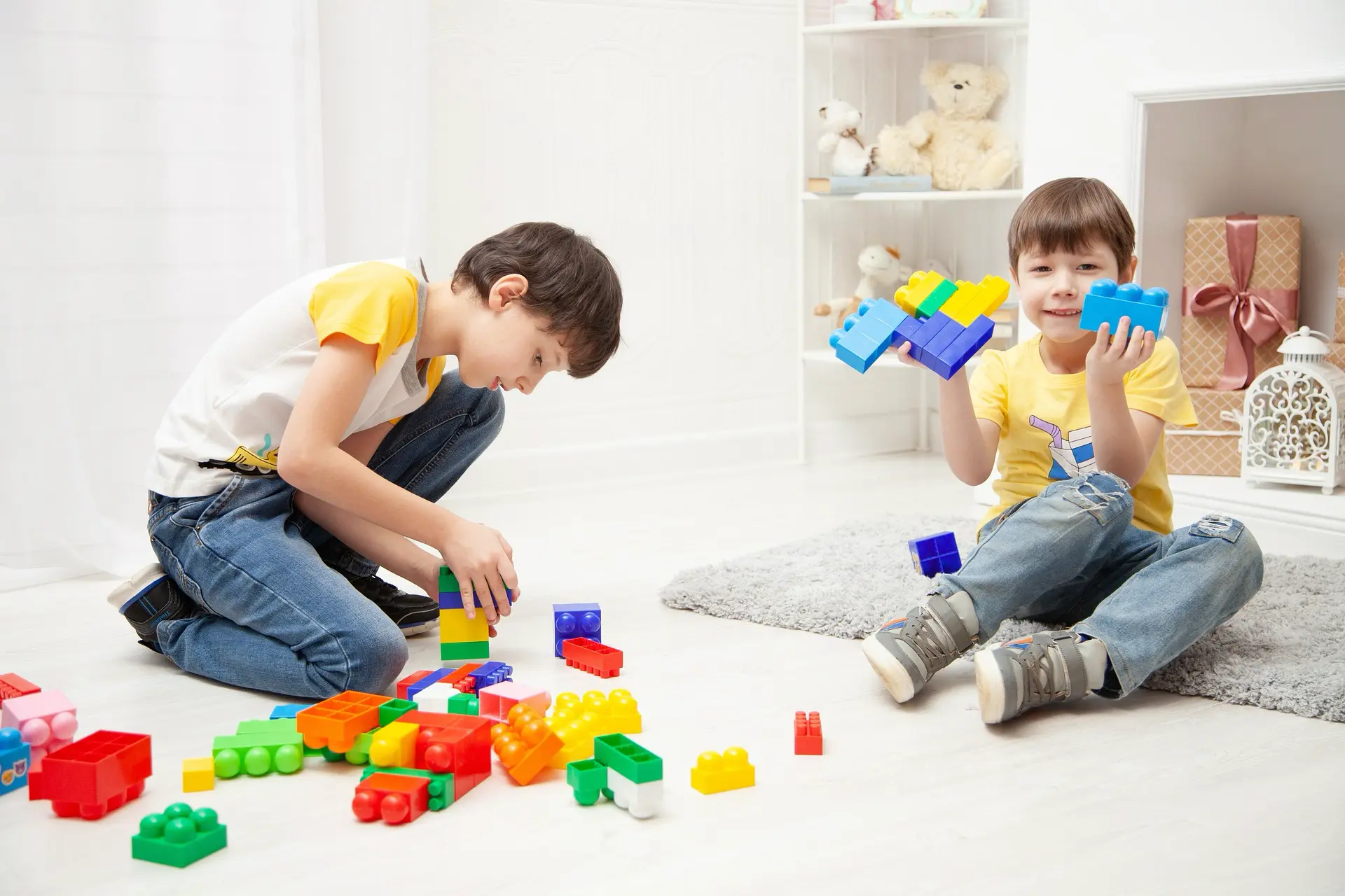 Children playing with building blocks spread across a living room floor