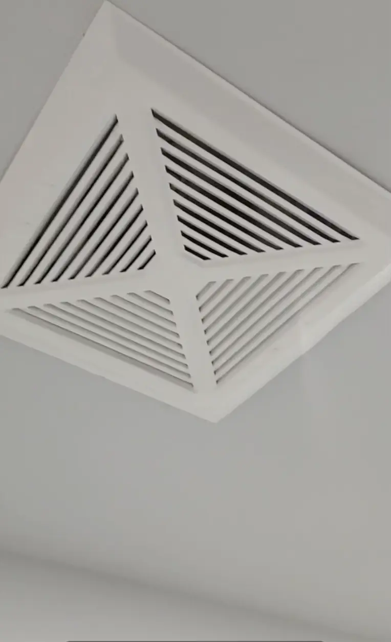 White ceiling air vent register in a home before winter cleaning