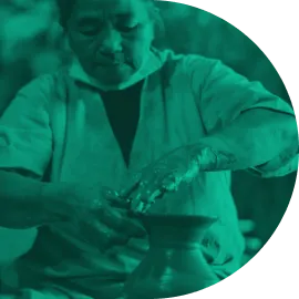 Person shaping clay on a pottery wheel, focusing intently on the craft.
