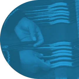 Close-up of hands weaving white threads on a loom.