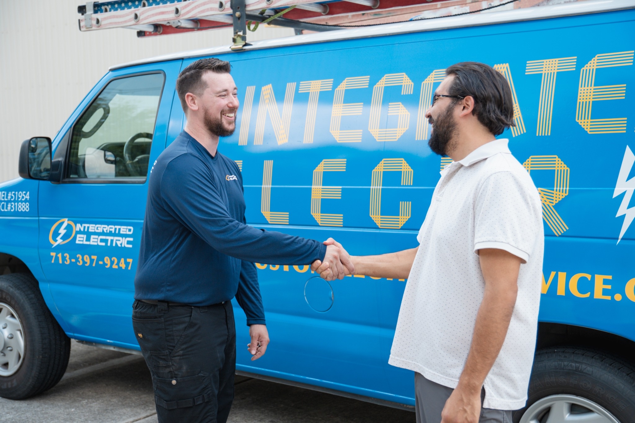 Integrated Electric electrician greeting a customer beside the company service van