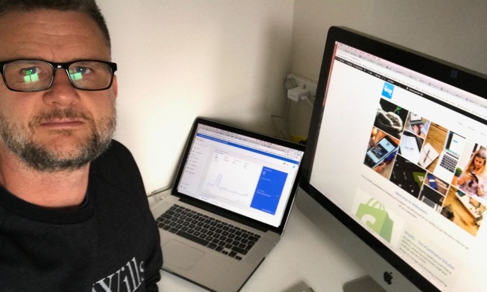 Steve sitting at desk with laptop showing analytics and a large monitor displaying an old version of the Webcetera website.