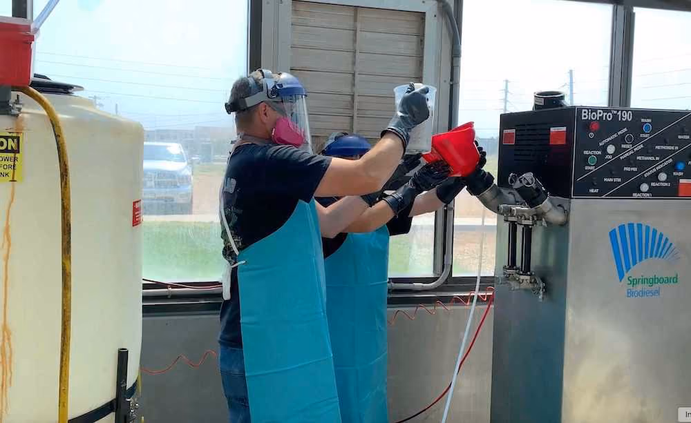 Two individuals operating a BioPro biodiesel processor from Springboard Biodiesel