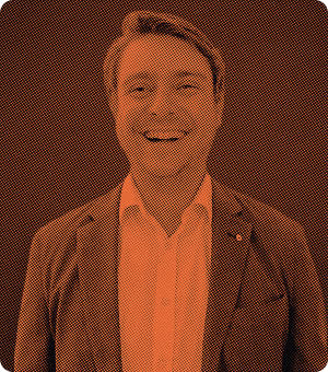 Smiling man wearing a suit jacket and white shirt against an orange and black halftone background.