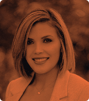 Portrait of a smiling woman with shoulder-length hair wearing a blazer.